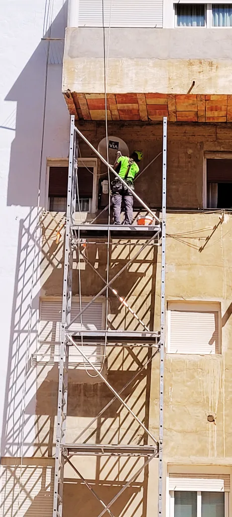 operario de trabajos verticales utilizando torre de trabajo móvil en pintura de patio interior