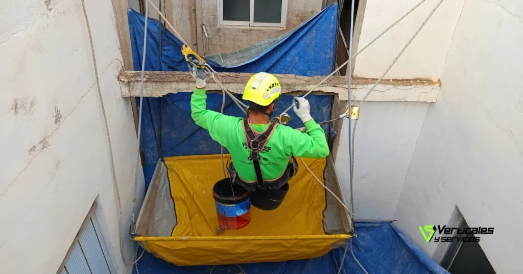 Operario de Verticales y Servicios ejecutando trabajos de rehabilitación de patio de luces interior y exterior.