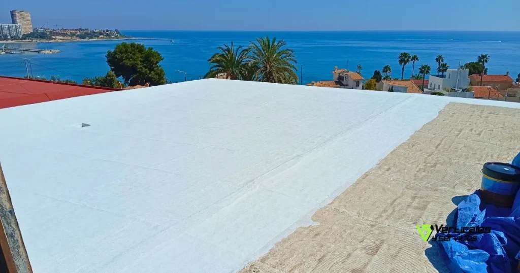 Proceso de impermeabilización de cubiertas de un tejado de un edificio frente al mar.